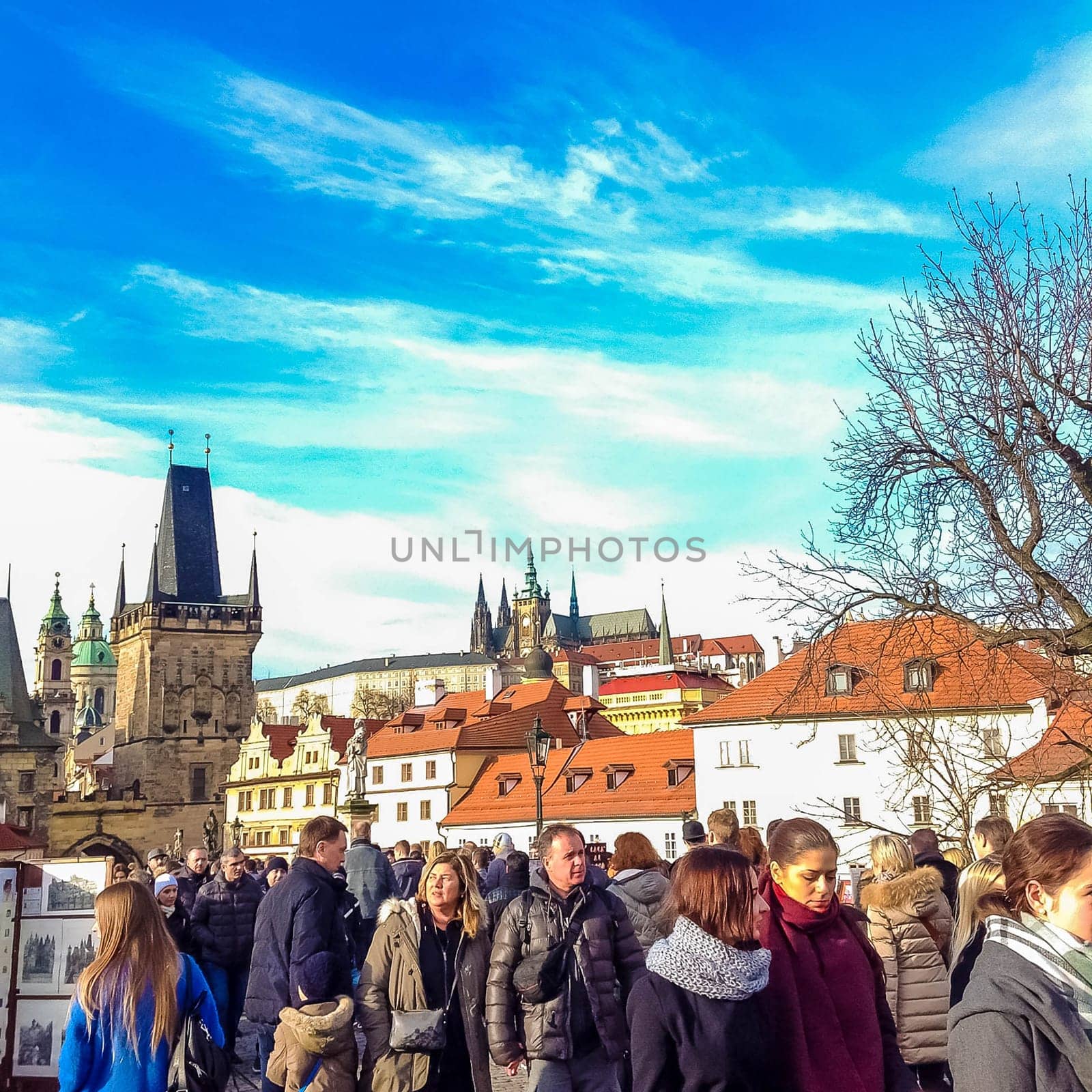 Prague, Czech Republic - December 31, 2017: People walking on the historic Charles Bridge that crosses the Vltava river overlooking its entrance tower.