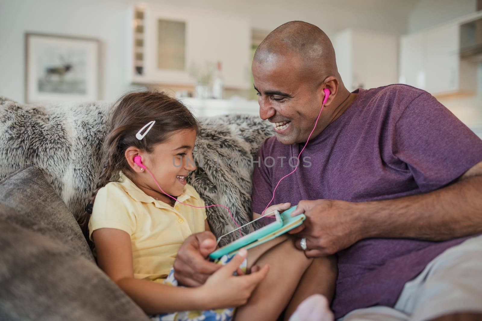 Father and daughter laughing together, using a digital touch screen tablet.