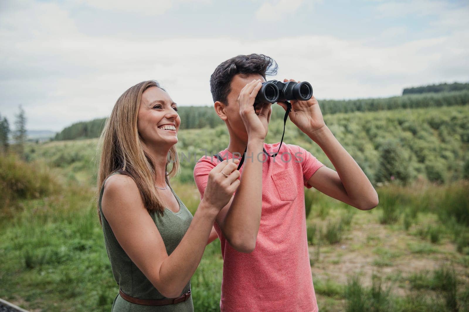 Mother helping son while he looks through the binoculars.