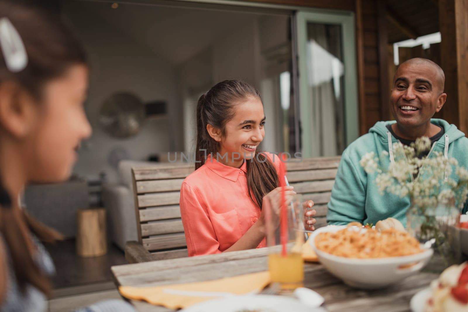 Little girl laughing with her family at the table outside holiday cottage.