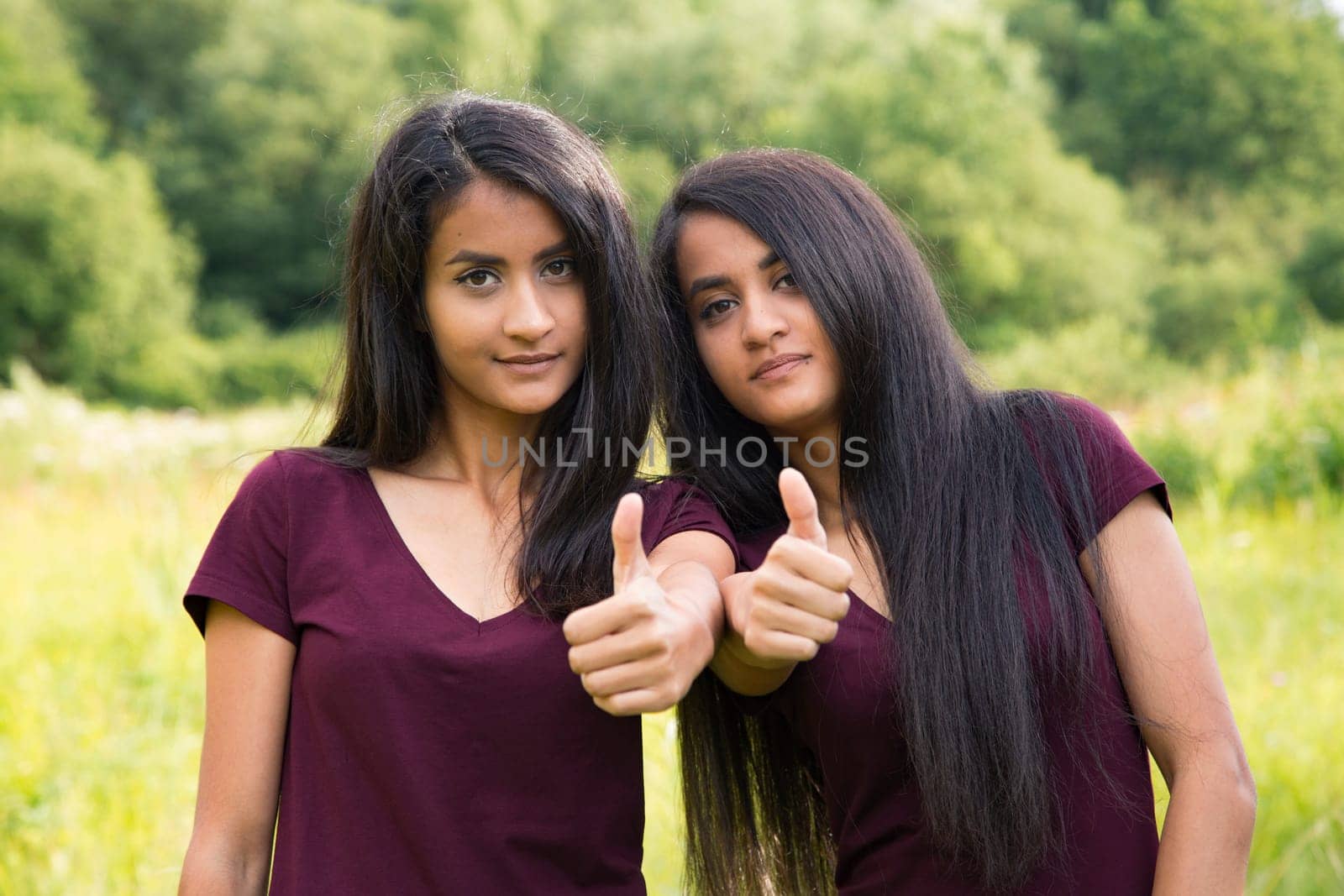 Twins keep thumbs up - outdoor view in summer