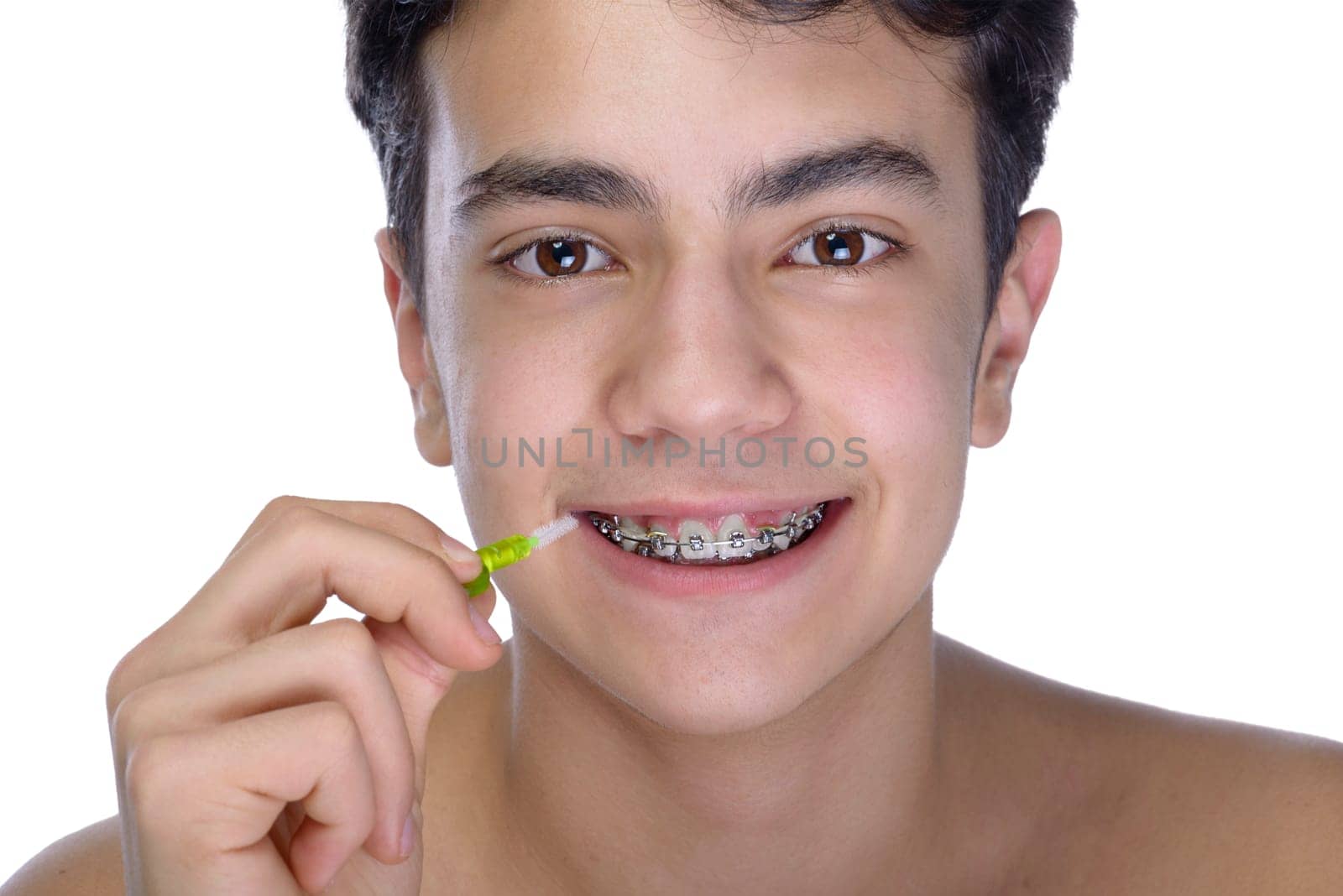 Cute teenager with white background, wearing braces on his teeth. Use a small toothbrush.