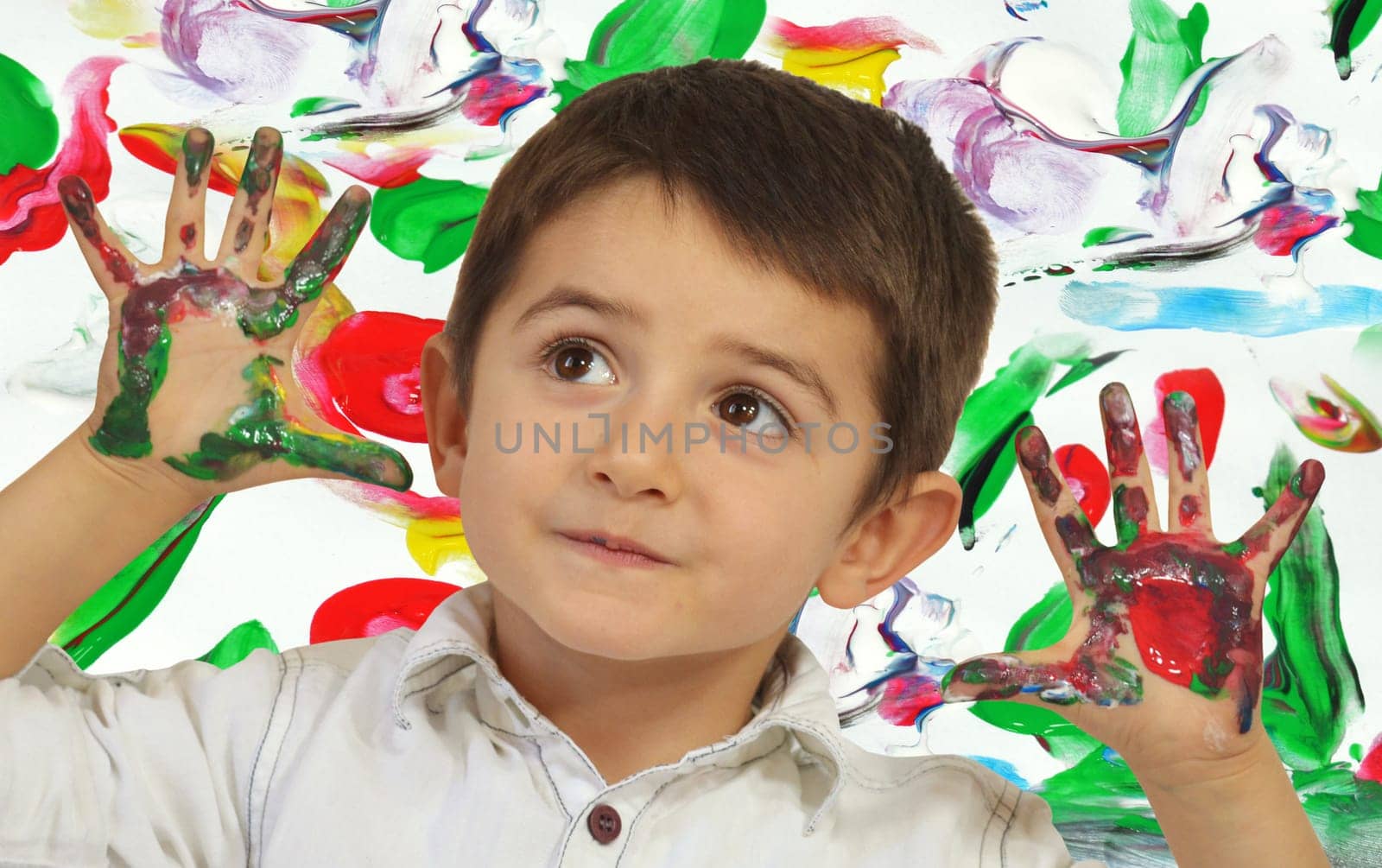 Little boy painting with hands with different color paint on his palms