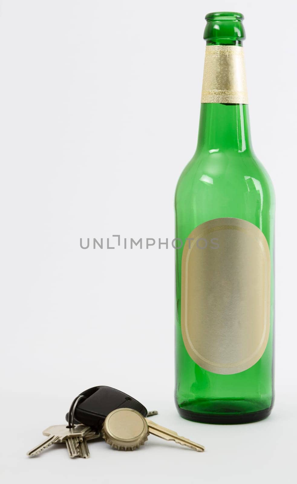 empty beer bottle with car key and crown cork isolated in grey background.