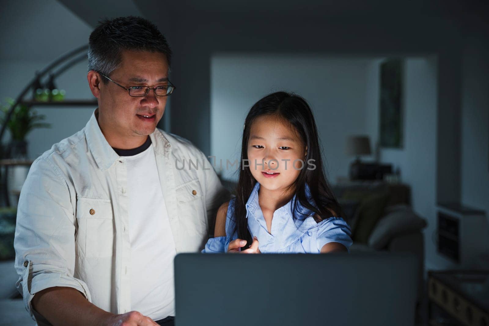 Little girl is getting help from her father while doing homework on the laptop at home.