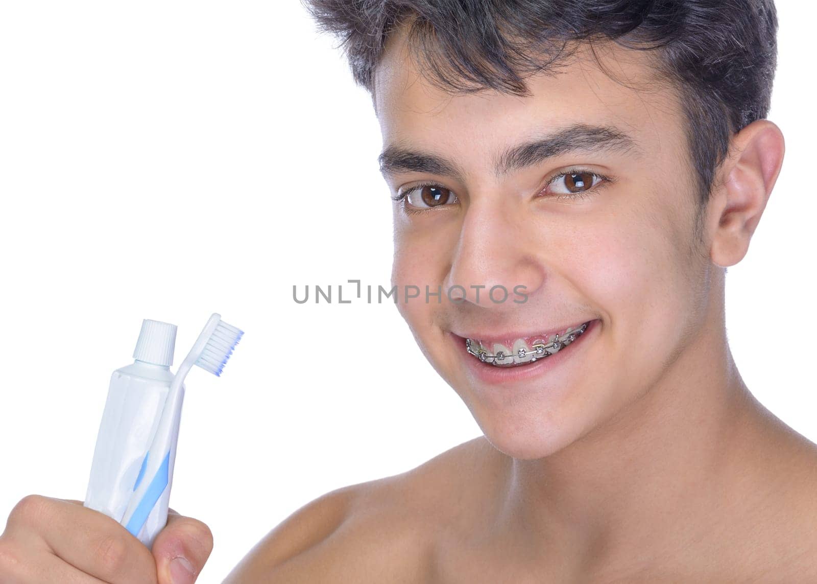 Cute teenager with white background, wearing braces on his teeth. Use toothbrush and toothbrush for cleaning.