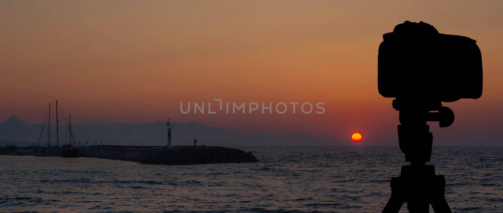 Camera on tripod with sea and sunset in background / Gouves, Crete, Greece