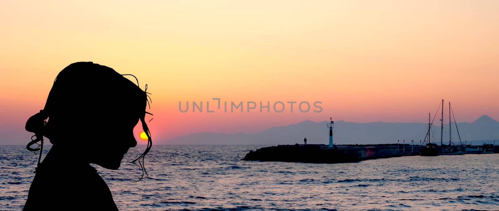 Silhouette of a young girl with sunset over the sea in Gouves, Crete, Greece