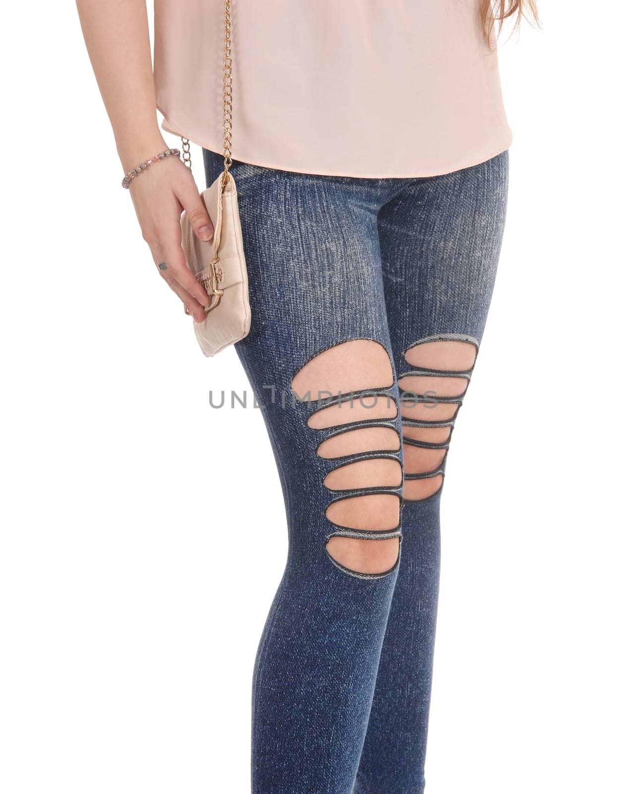 A closeup image of the legs in jeans of a young woman standing with.her purse, with holes in the jeans, isolated for white background.