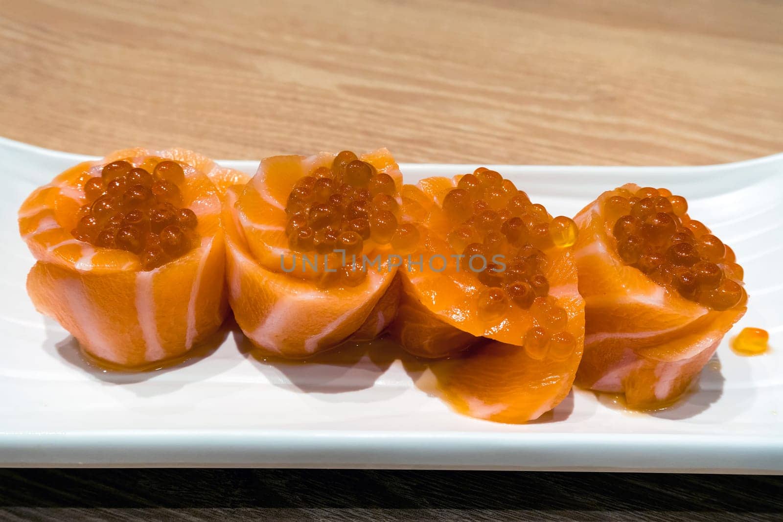 Fresh raw Salmon fish Sushi roll with Salmon Roe on white ceramic plate closeup macro