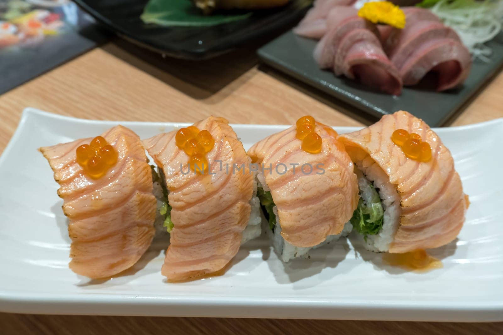 Seared Fresh Raw Salmon Sushi Nigiri Roll with fish roe on white plate closeup macro
