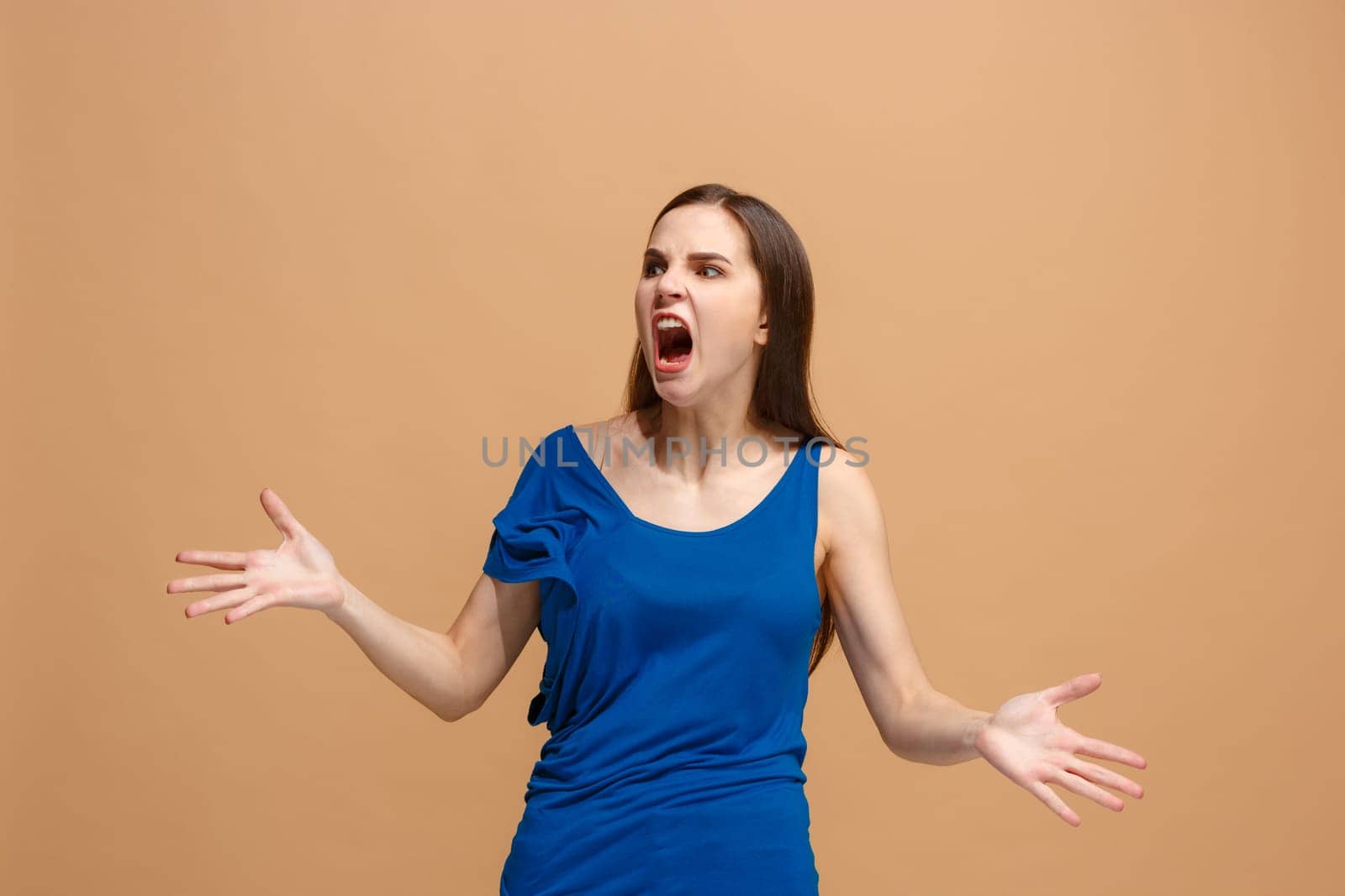 Screaming, hate, rage. Crying emotional angry woman screaming on pastel studio background. Emotional, young face. Female half-length portrait. Human emotions, facial expression concept. Trendy colors