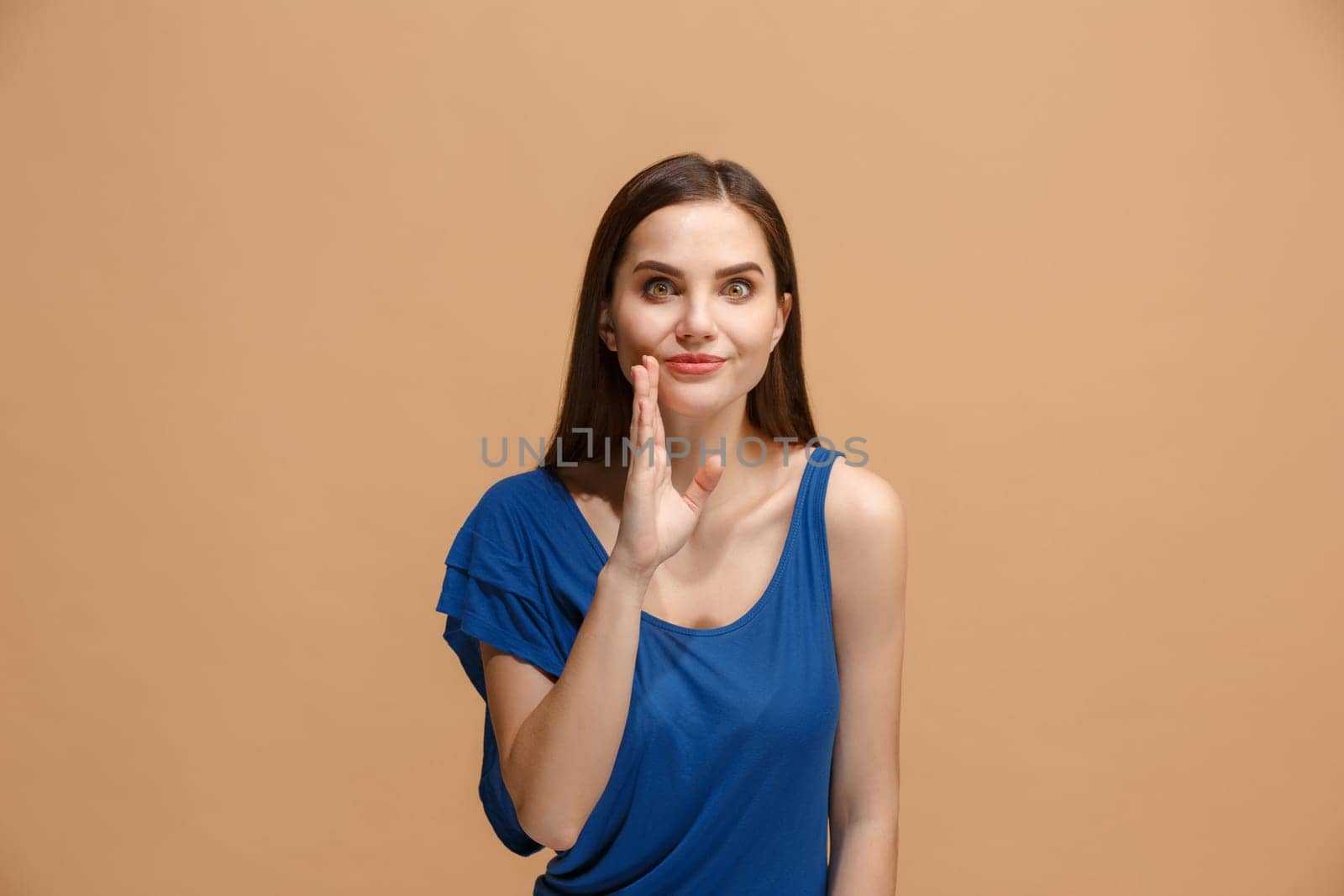 Secret, gossip concept. Young woman whispering a secret behind her hand. Business woman isolated on trendy pastel studio background. Young emotional woman. Human emotions, facial expression concept.
