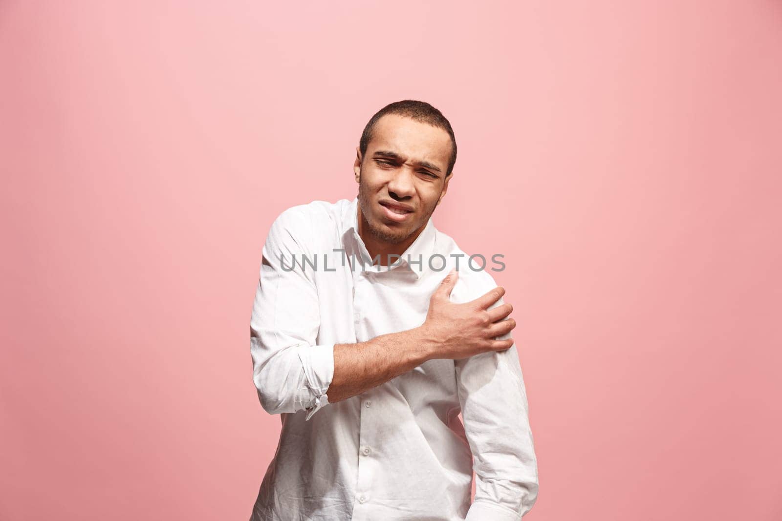 Pain concept. Beautiful male portrait isolated on pink backgroud. Young emotional surprised afro man looking at camera.Human emotions, facial expression concept. man overwhelmed with pain in shoulder