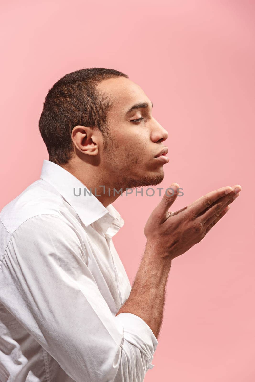 I kiss you. Portrait of attractive man with kiss on lips. Pink studio. . Profile male portrait. Young happy emotional funny afro man looking at camera. Human facial emotions concept. Trendy colors