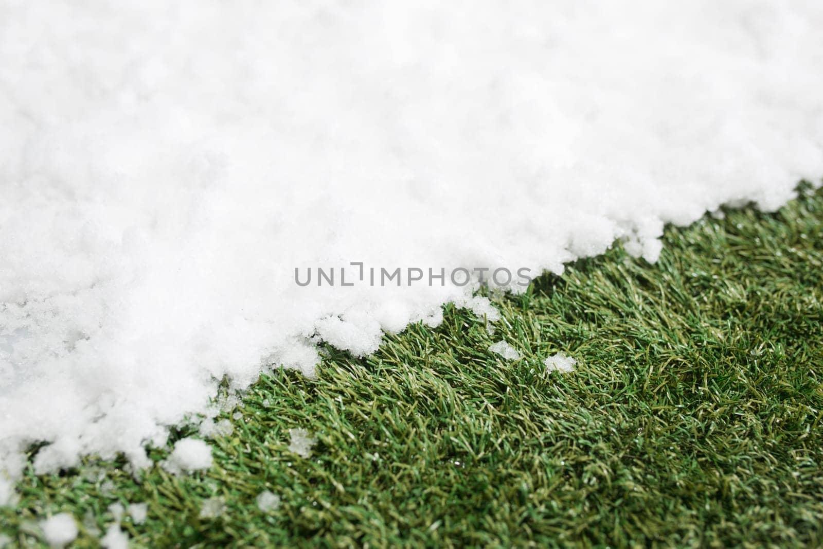 Meeting white snow and green grass close up - between winter and spring concept background. Conceptual image about spring. Selective focus. Background with copy space