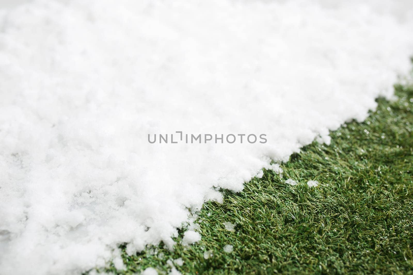 Meeting white snow and green grass close up - between winter and spring concept background. Conceptual image about spring. Selective focus. Background with copy space