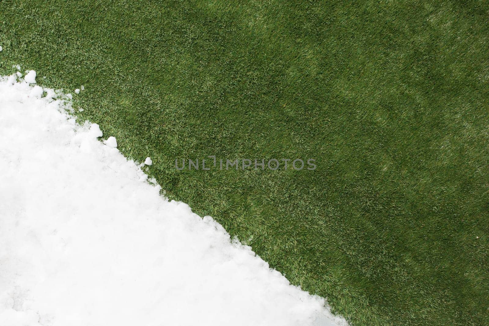 Meeting white snow and green grass close up - between winter and spring concept background. Conceptual image about spring. Selective focus. Background with copy space. Top view