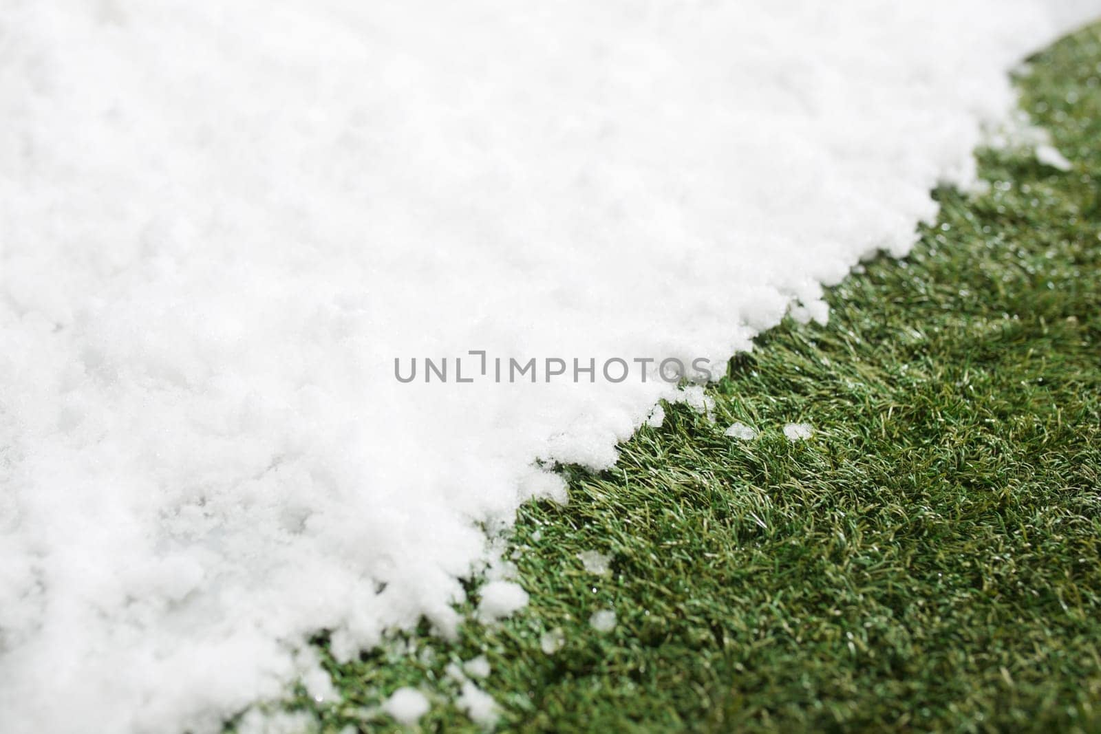Meeting white snow and green grass close up - between winter and spring concept background. Conceptual image about spring. Selective focus. Background with copy space