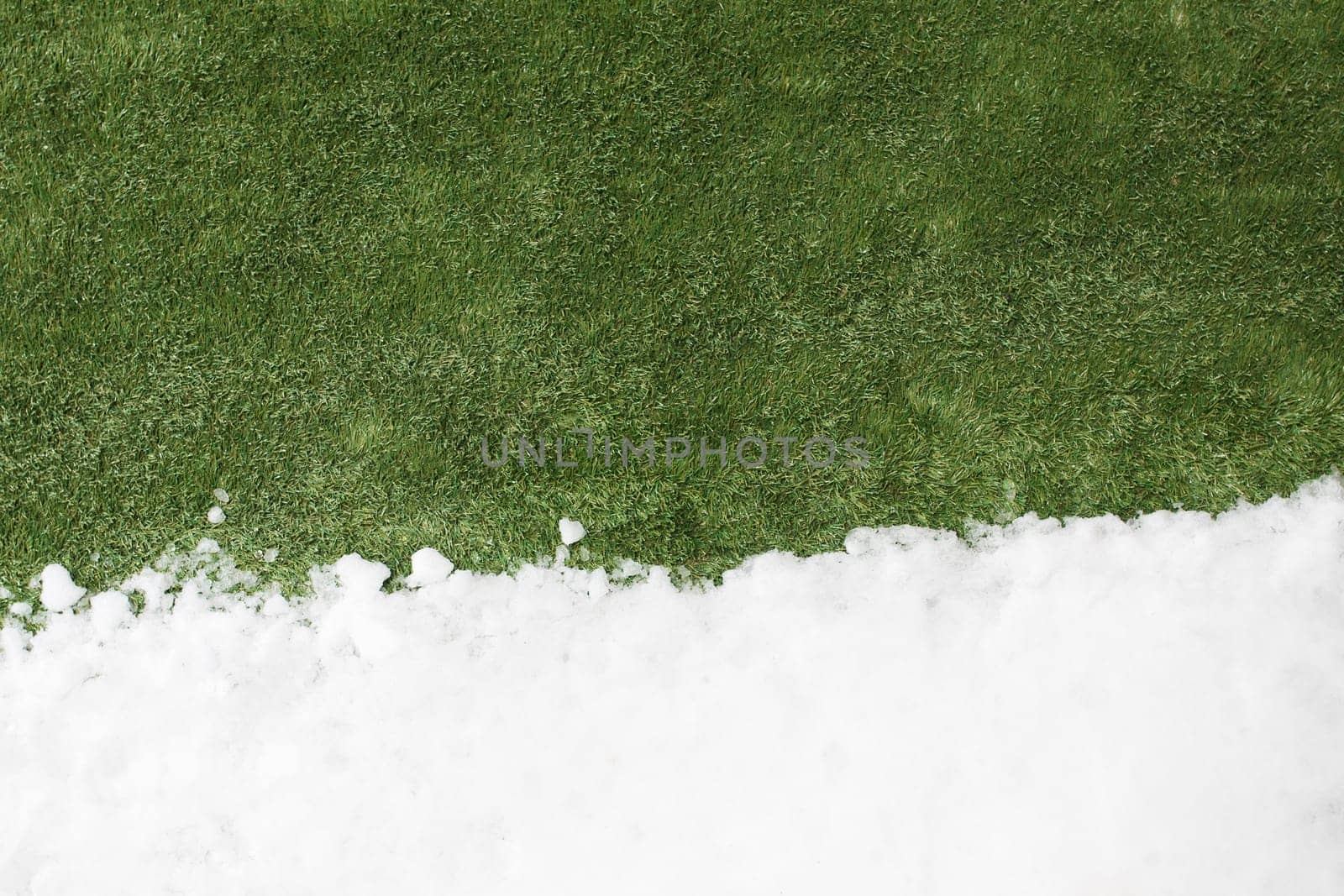Meeting white snow and green grass close up - between winter and spring concept background. Conceptual image about spring. Selective focus. Background with copy space