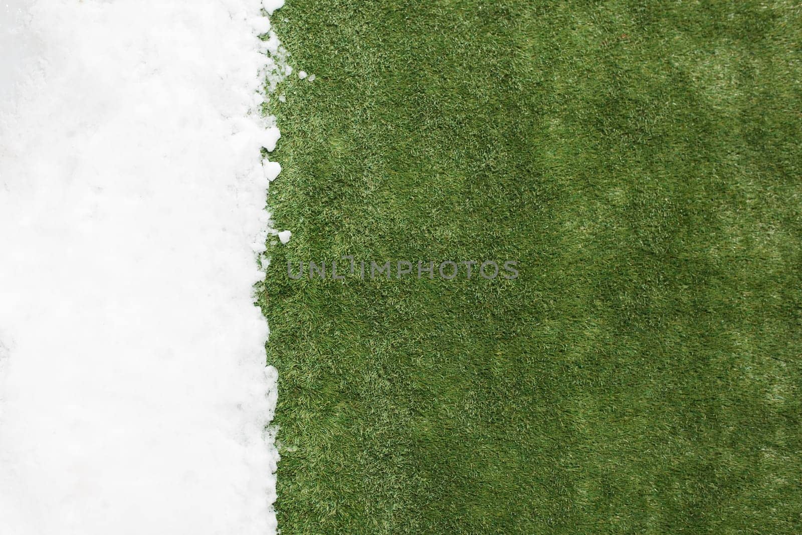 Meeting white snow and green grass close up - between winter and spring concept background. Conceptual image about spring. Selective focus. Background with copy space. Top view