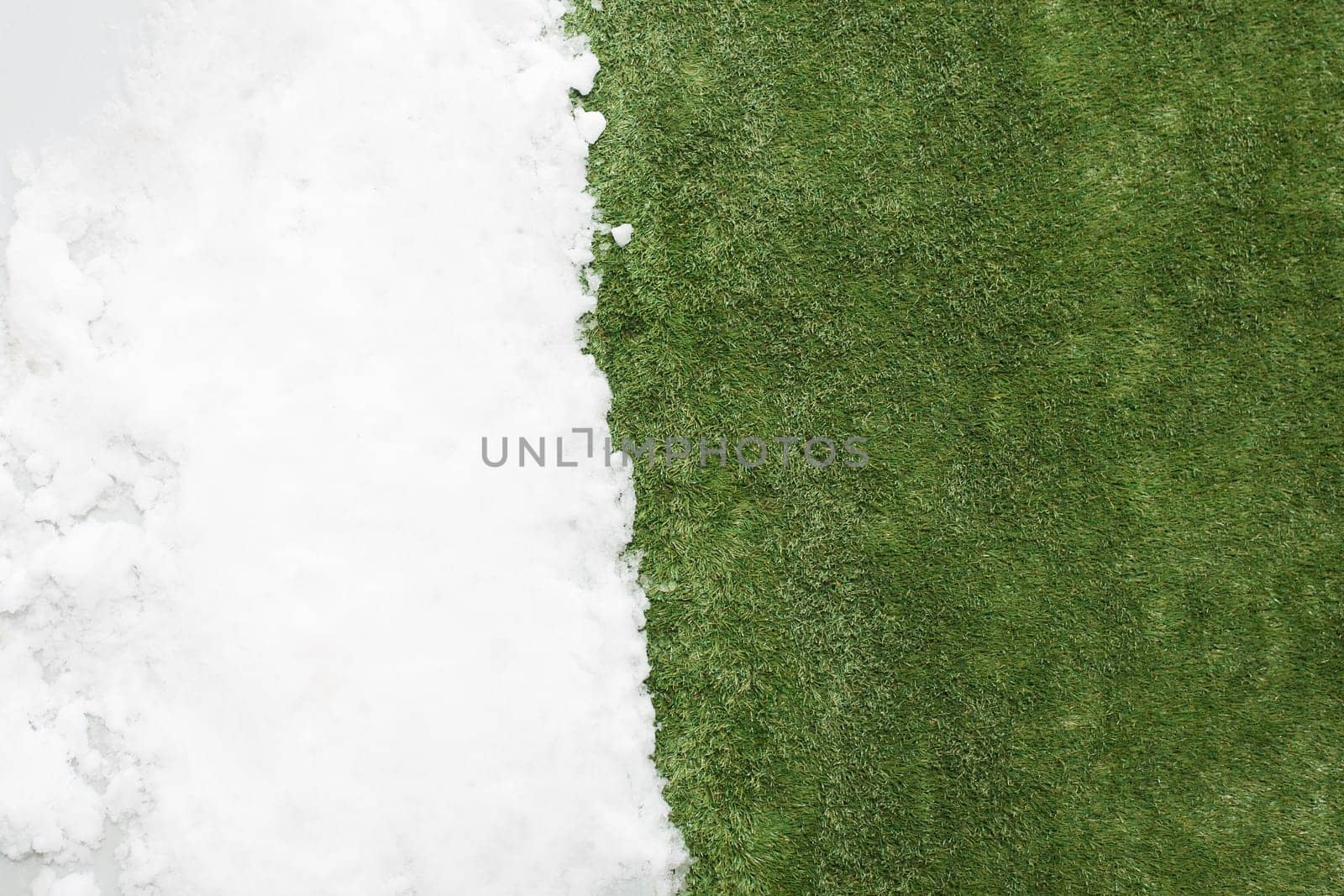 Meeting white snow and green grass close up - between winter and spring concept background. Conceptual image about spring. Selective focus. Background with copy space. Top view