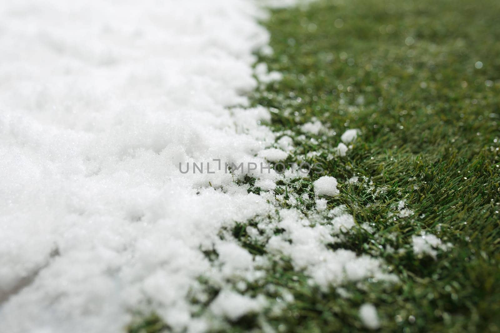 Meeting white snow and green grass close up - between winter and spring concept background. Conceptual image about spring. Selective focus. Background with copy space