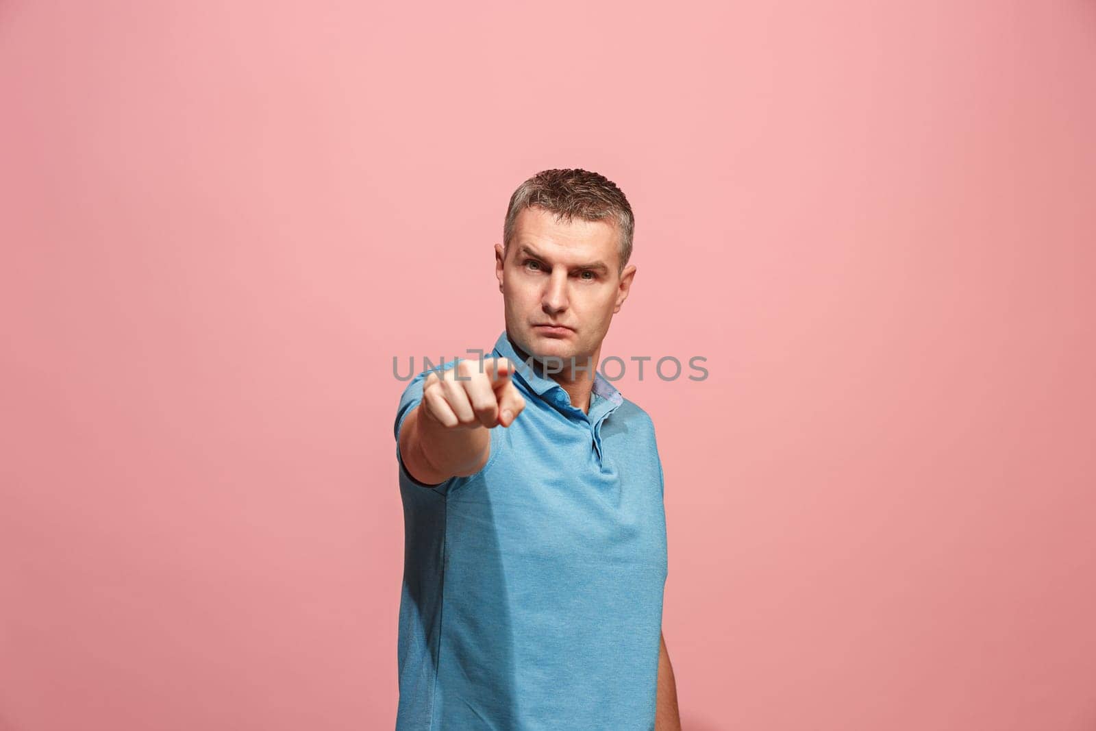 I choose you and order. The serious business man point you, want you, half length closeup portrait on pink studio background. The human emotions, facial expression concept. Front view. Trendy colors