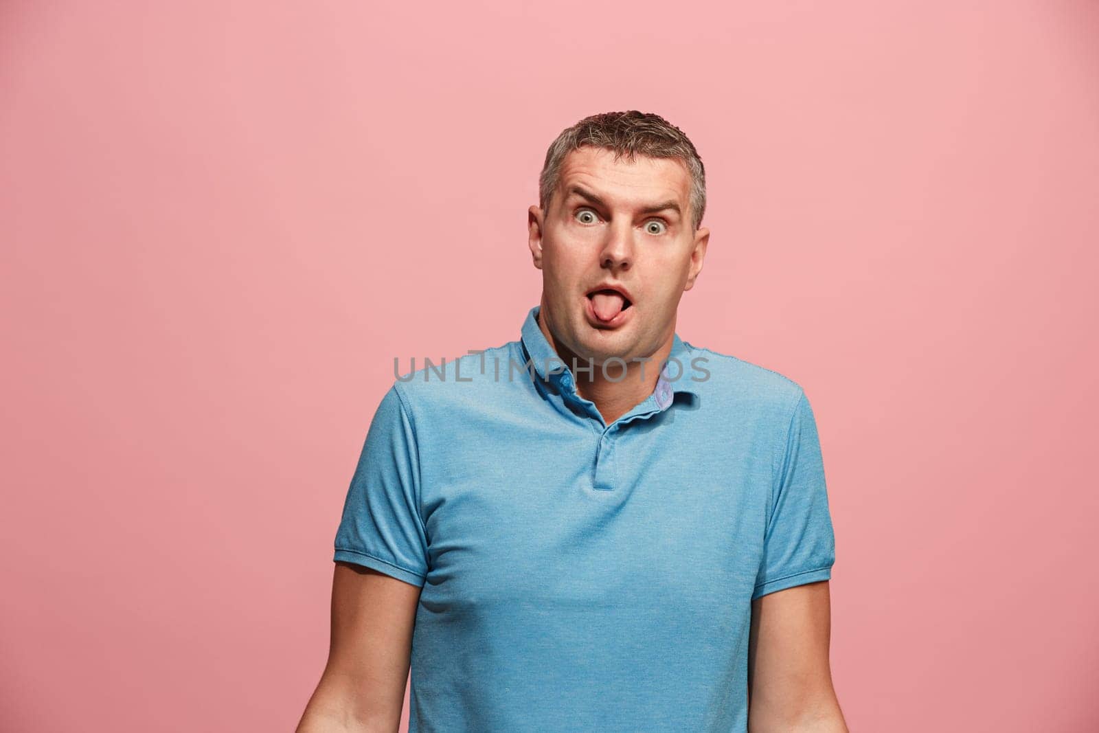 I lost my mind. The squint eyed man with weird expression. Beautiful male half-length portrait isolated on pink studio backgroud. The crazy man. The human emotions, facial expression concept.