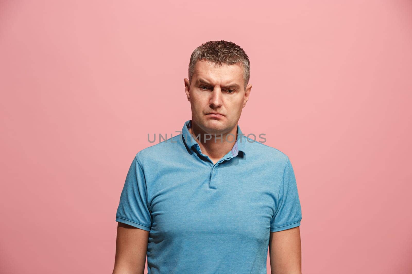 Suspicion. Doubt, mistrust, distrust concept. Doubtful man looking with disbelief expression . Young emotional man. Human emotions, facial expression concept. Studio. Isolated on trendy pink