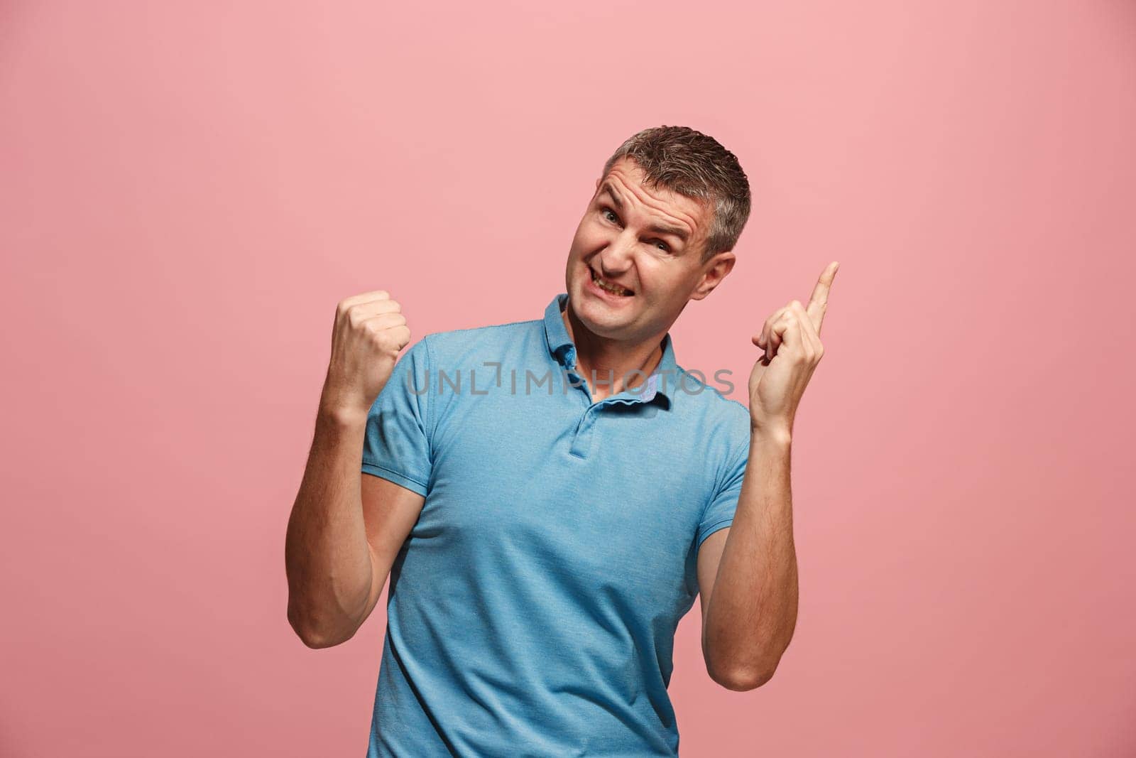 I won. Winning success happy man celebrating being a winner. Dynamic image of caucasian male model on pink studio background. Victory, delight concept. Human facial emotions concept. Trendy colors