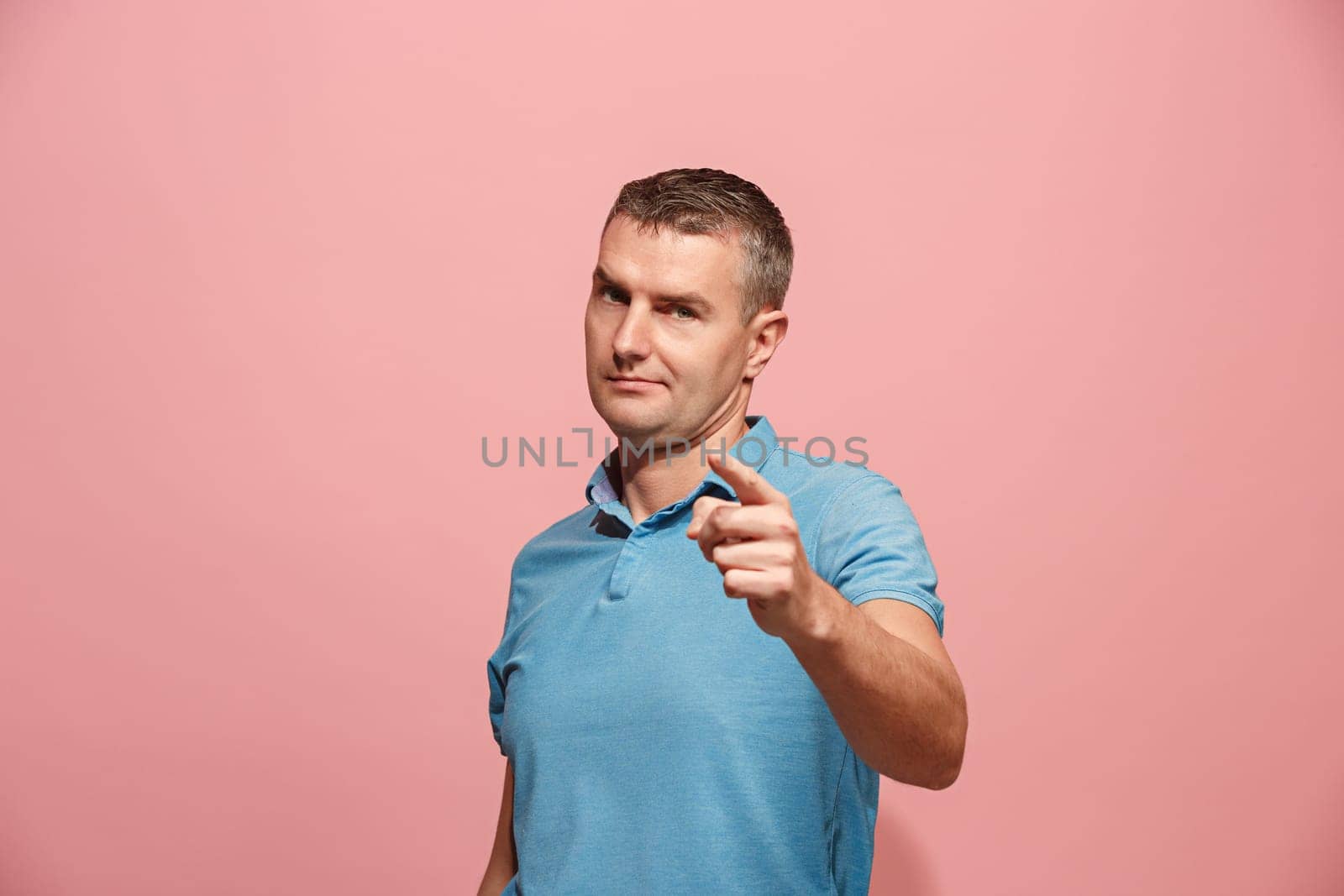 I choose you and order. The serious business man point you, want you, half length closeup portrait on pink studio background. The human emotions, facial expression concept. Front view. Trendy colors