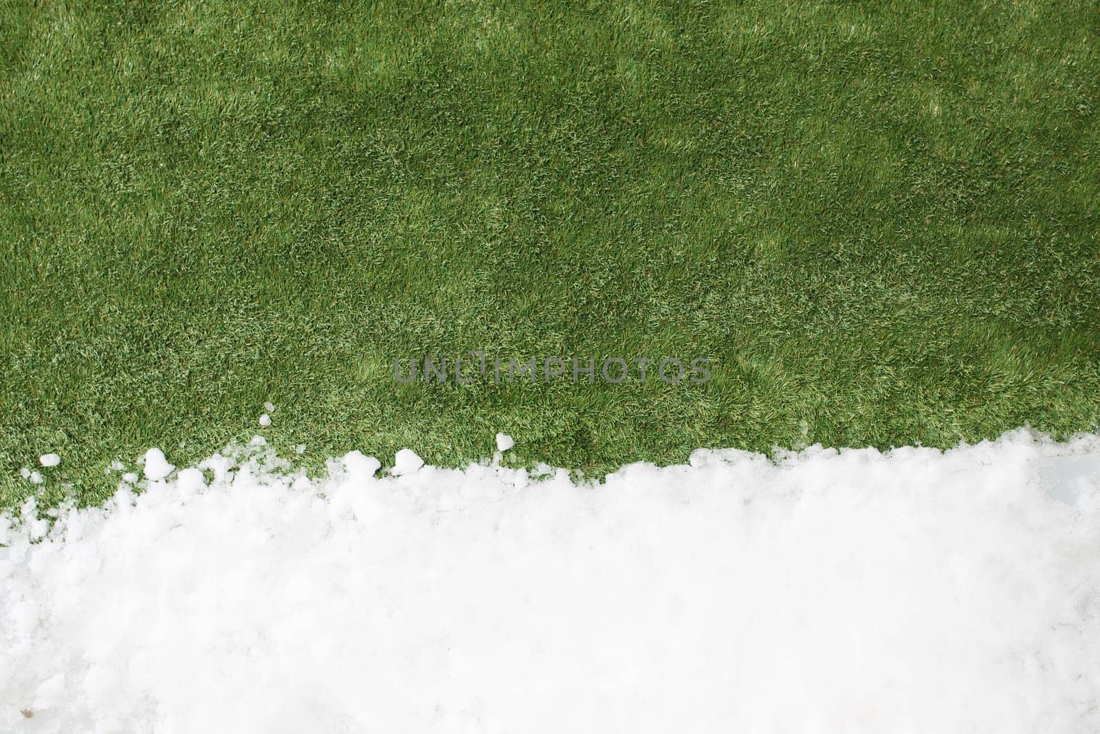 Meeting white snow and green grass close up - between winter and spring concept background. Conceptual image about spring. Selective focus. Background with copy space