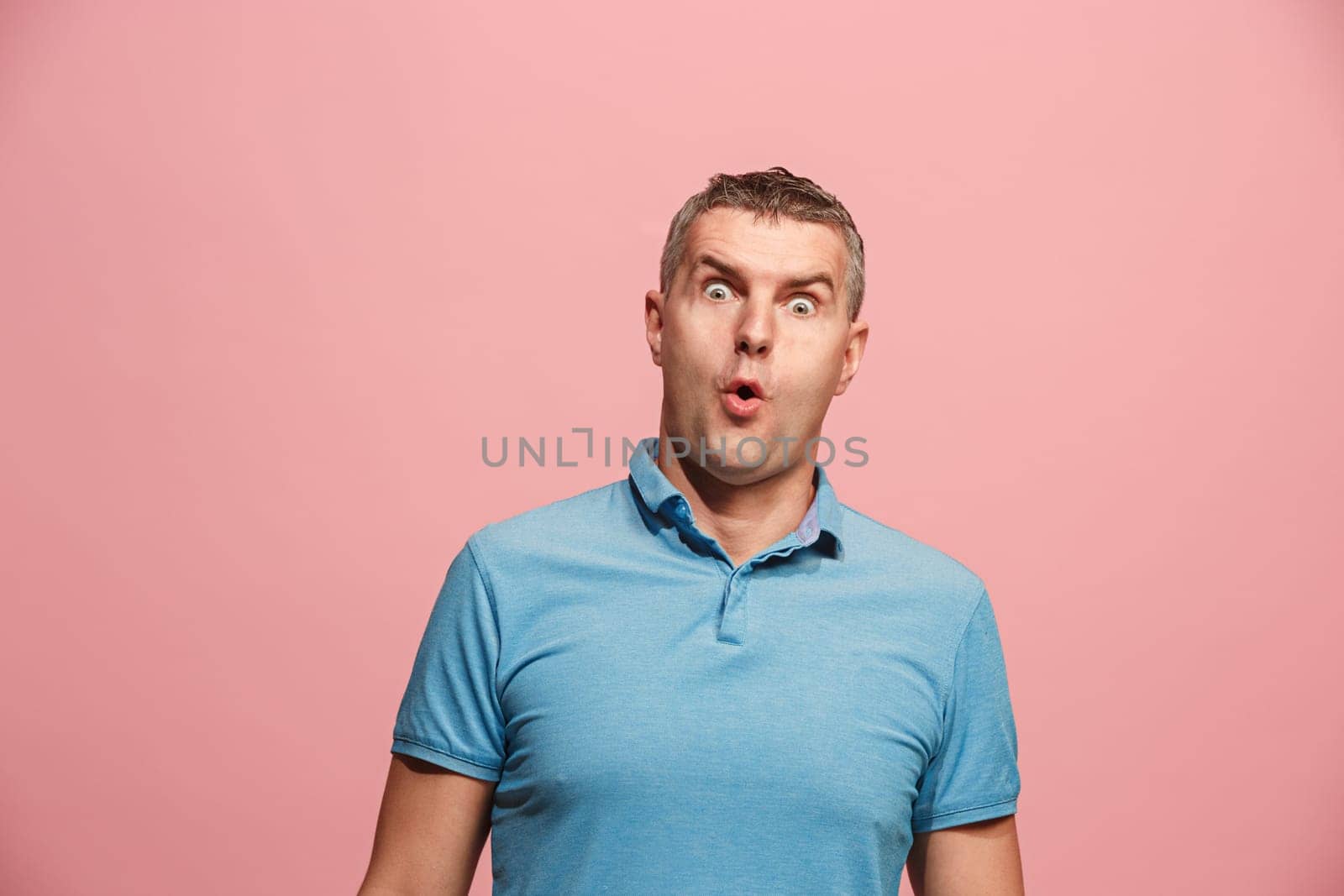 Wow. Attractive male half-length front portrait on pink studio backgroud. Young emotional surprised bearded man standing with open mouth. Human emotions, facial expression concept. Trendy colors