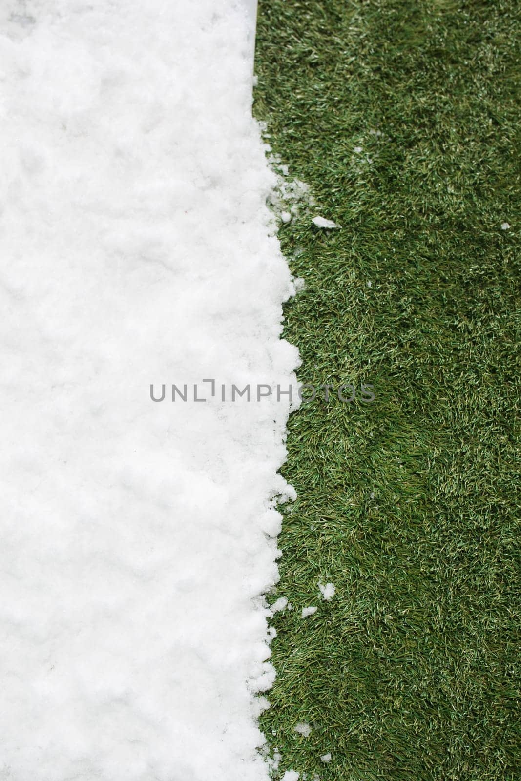 Meeting white snow and green grass close up - between winter and spring concept background. Conceptual image about spring. Selective focus. Background with copy space