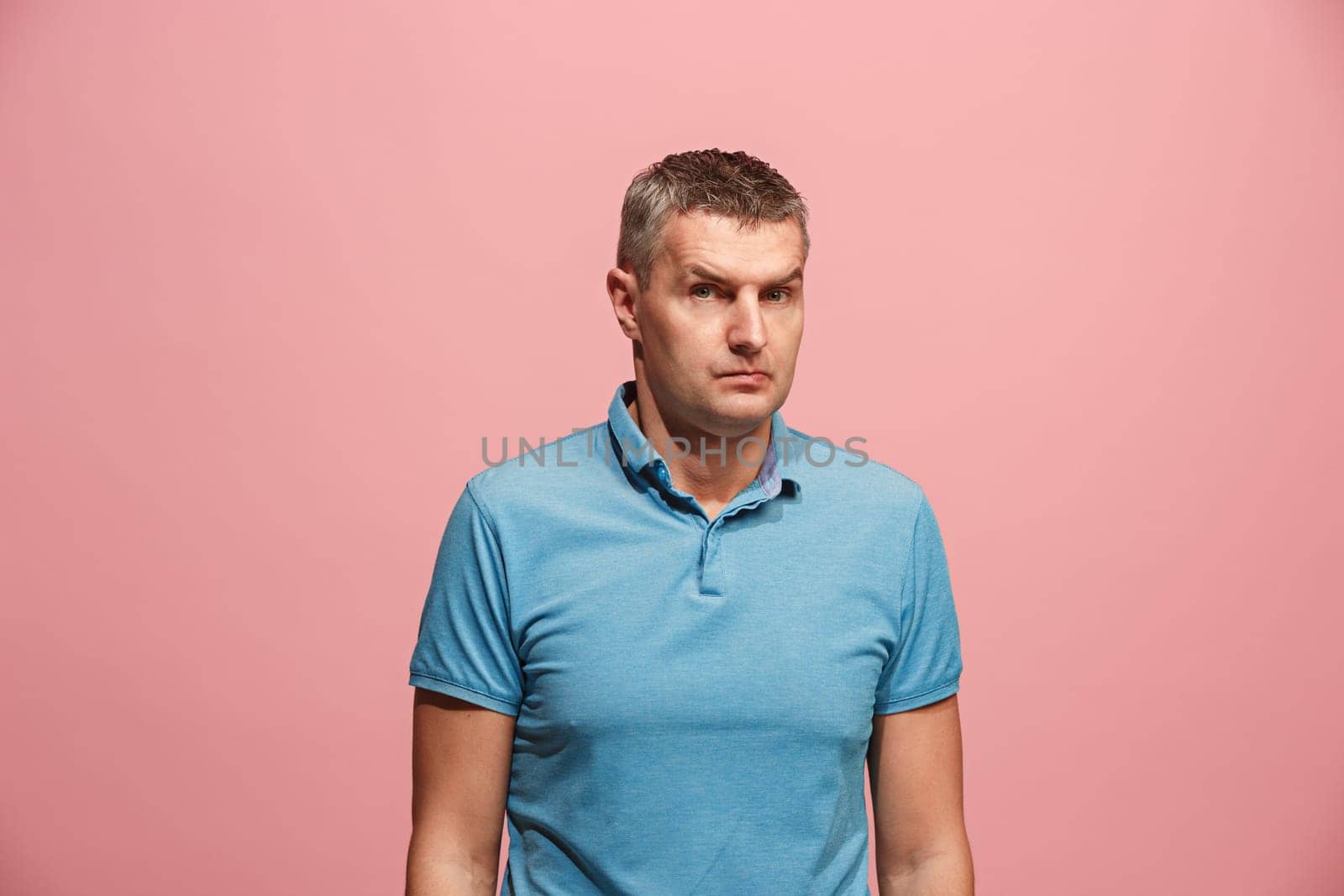Suspicion. Doubt, mistrust, distrust concept. Doubtful man looking with disbelief expression . Young emotional man. Human emotions, facial expression concept. Studio. Isolated on trendy pink