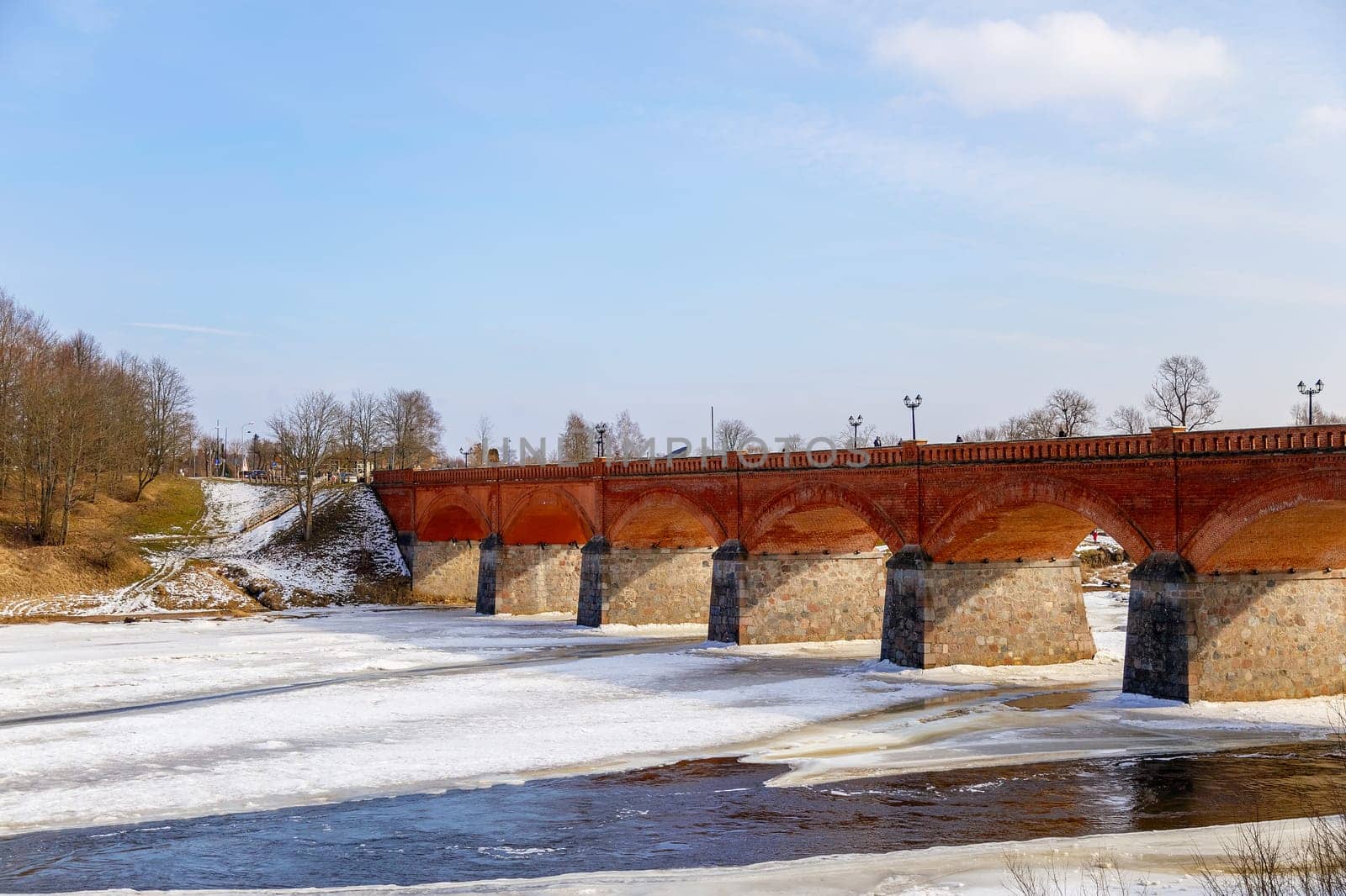 The first spring thawed patches on the river,against the backdrop of a stone bridge