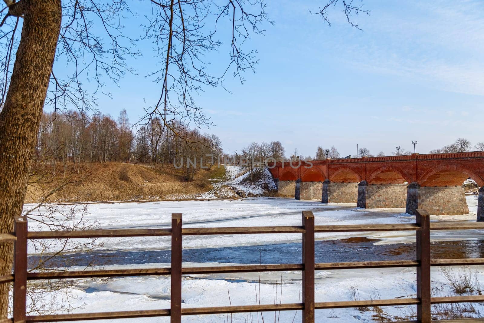 The first spring thawed patches on the river,against the backdrop of a stone bridge
