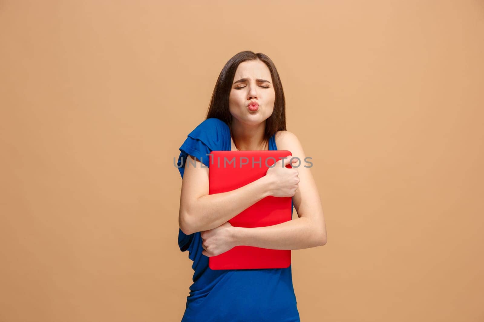 Businesswoman hugging laptop. Love to computer concept. Attractive female half-length front portrait, trendy pastel studio backgroud. Young emotional pretty woman. Human emotions, facial expression concept.