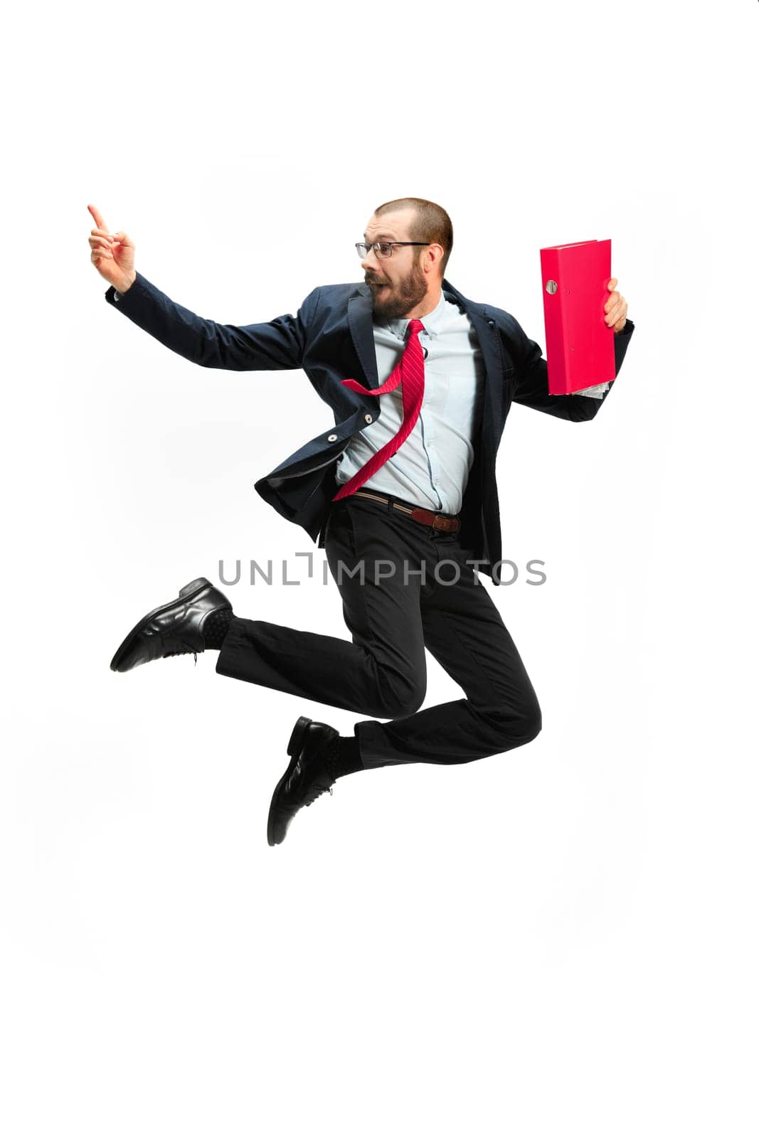 Funny cheerful businessman jumping in air over white studio background. Jump of happy bearded young man in glasses, suit. Business, career, success, win concept. Victory, delight concept. Human facial emotions