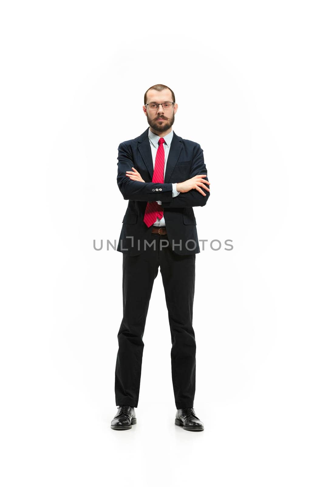 Full body or full-length portrait of businessman with red folder on white studio background. Serious bearded young man in glasses, suit, red tie standing in office. Business, career, success concept.