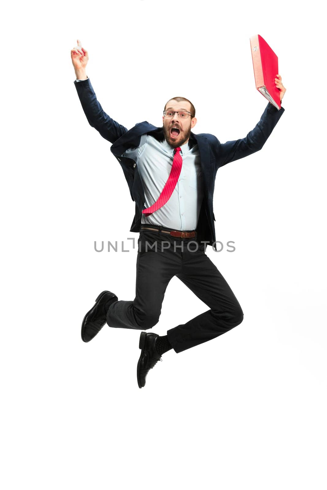 Funny cheerful businessman jumping in air over white studio background. Jump of happy bearded young man in glasses, suit. Business, career, success, win concept. Victory, delight concept. Human facial emotions