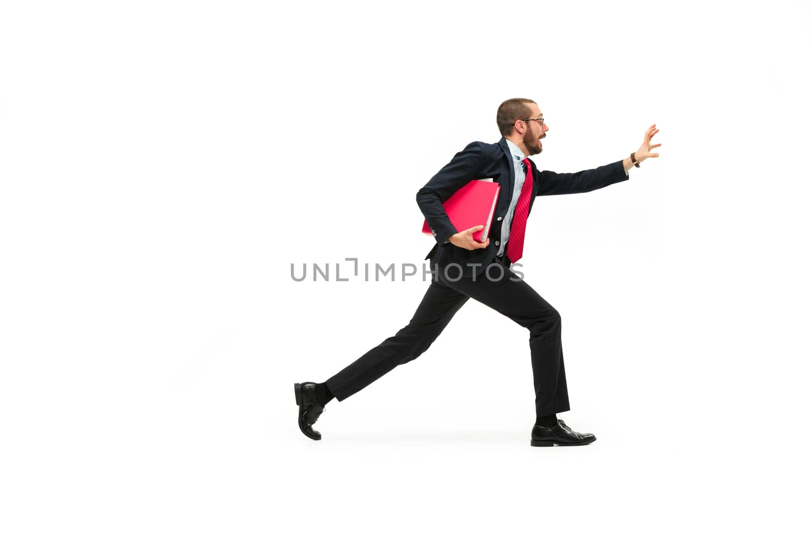 Businessman running with a folder isolated on white background. Full body or full-length portrait of businessman with red folder at studio background. Serious bearded young man in glasses, suit . Business, career, success concept. Profile