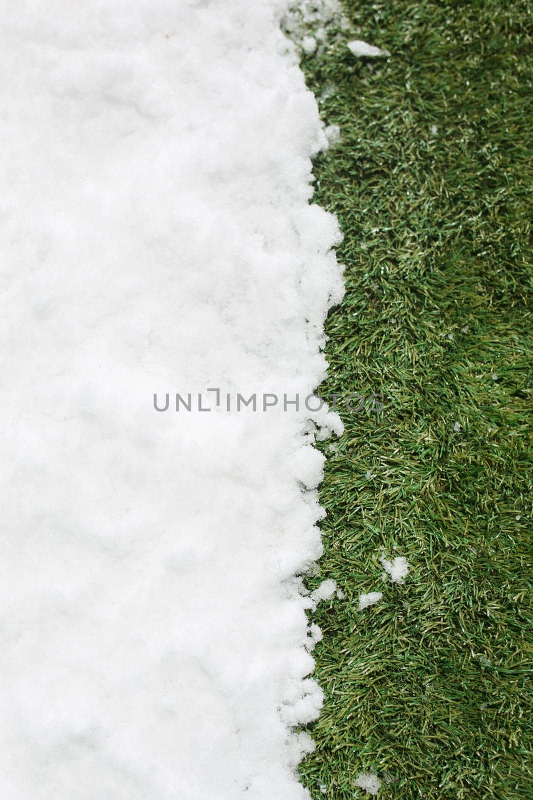 Meeting white snow and green grass close up - between winter and spring concept background. Conceptual image about spring. Selective focus. Background with copy space