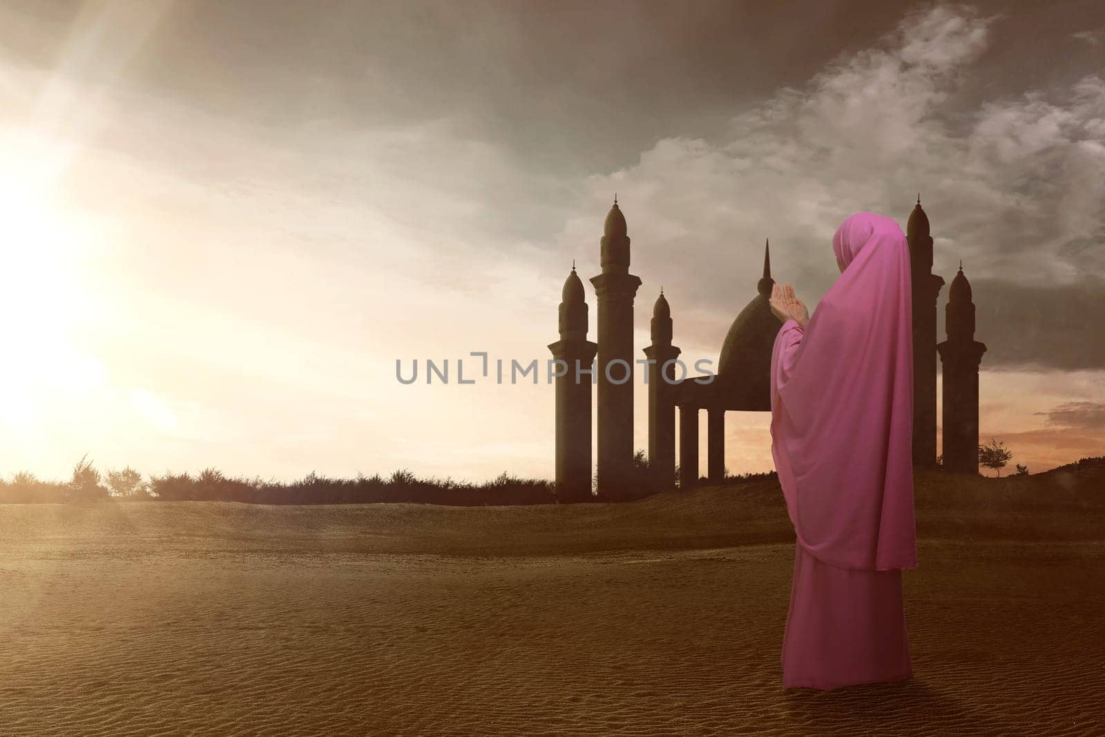 Rear view of asian muslim woman with veil pray to god during sunset