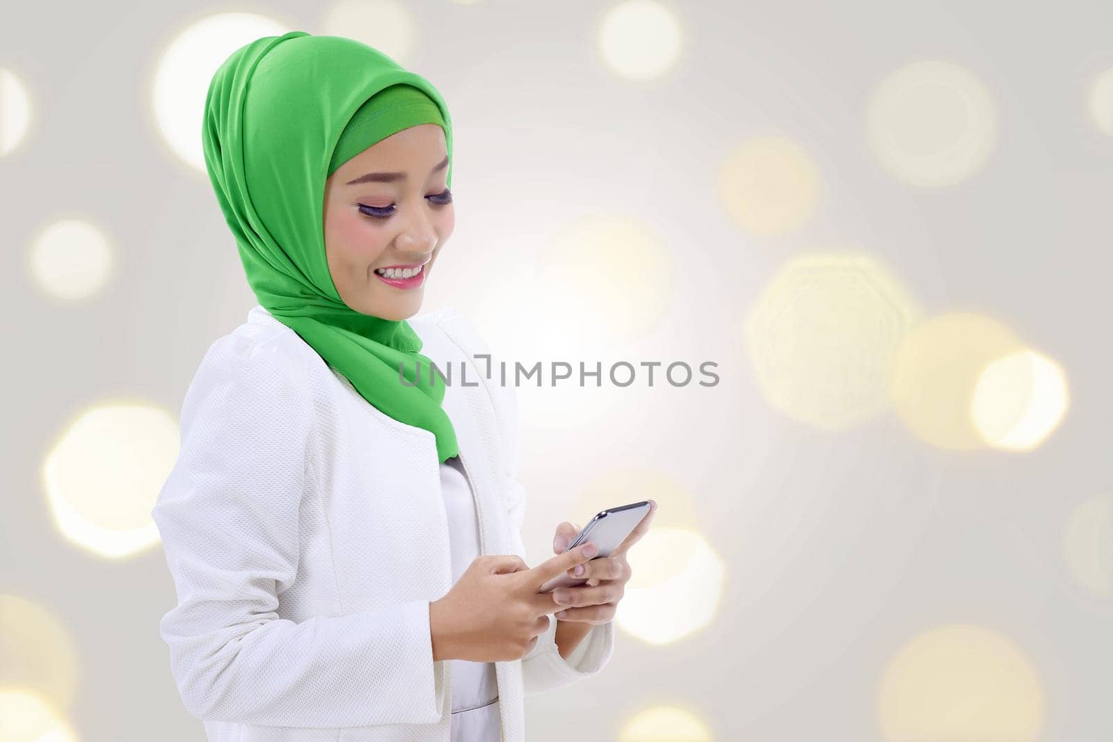 Happy asian muslim woman holding a phone over blur light background