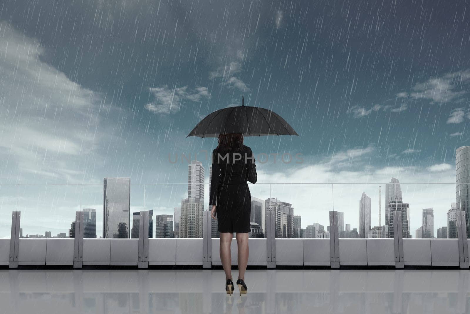 Business woman with umbrella in the rain on the city