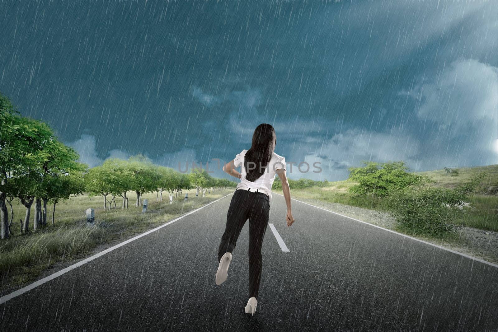 Businesswoman is moving forward under the rain with dark sky background