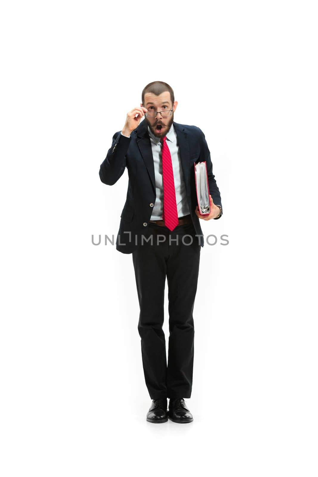 Full body or full-length portrait of businessman on white studio background. Surprised bearded young man in glasses, suit, red tie standing in office. Business, career, success concept.