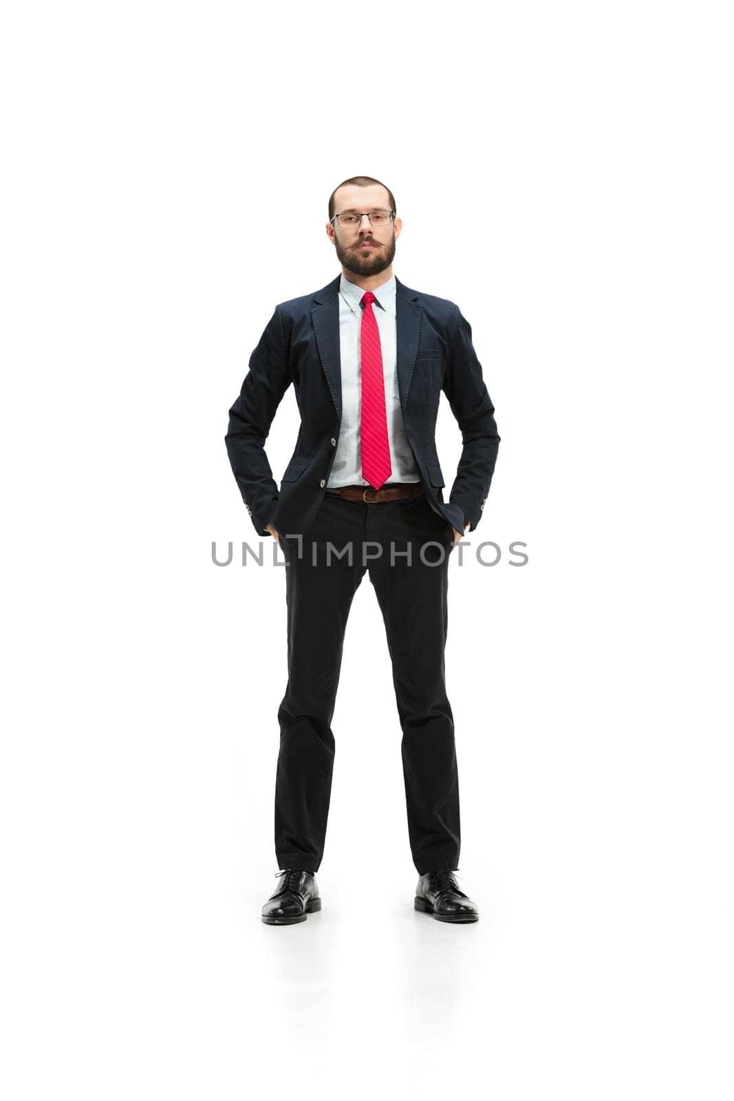 Full body or full-length portrait of businessman on white studio background. Serious bearded young man in glasses, suit, red tie standing in office. Business, career, success concept.